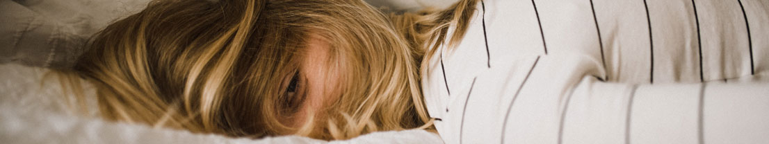 Wissensbeitrag: Schlafförderung durch Binaurale Beats, Frau liegt im Bett