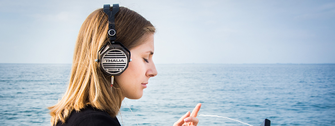 Woman with headphones by the sea, music and binaural beats