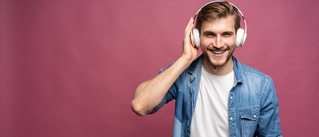 Glücklicher Mann hört Sound über Kopfhörer, roter Hintergrund