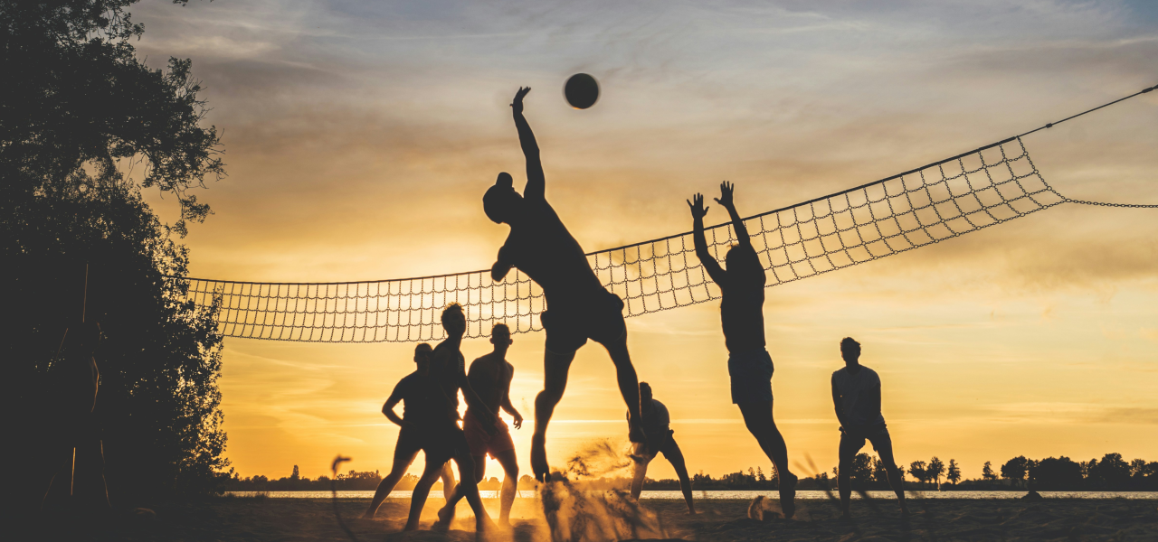 Gruppe von Freunden, die beim Volleyball Stress abbaut: Sport als Stressbewältigung