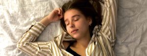 Eine junge Frau liegt schlafend auf einem Bett.