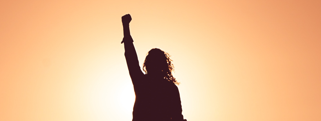 Silhouette einer Frau die kraftvoll die Faust in die Höhe streckt. Sie sieht aus, als wäre sie sich ihrer Fähigkeiten sicher. Dazu gehört es auch, die Kontrolle über die eigenen Gedanken zu haben und Grübeln zu stoppen