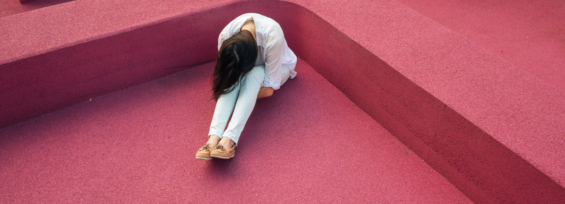 Frau sitzt auf dem Boden, Burnout Symptome bei Frauen