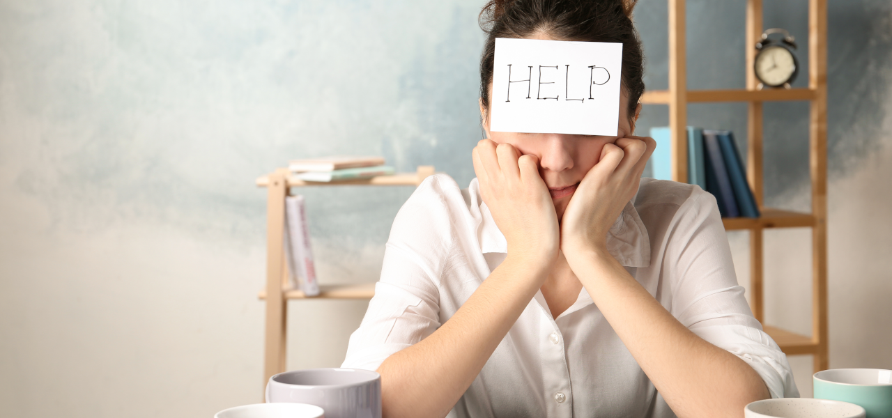 Symptome für ein Burnout, Frau hat Zettel auf der Stirn kleben mit dem Wort "HELP"